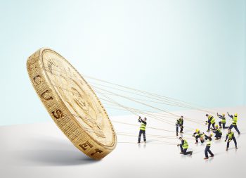 Group of builders carrying a large gold Pound coin